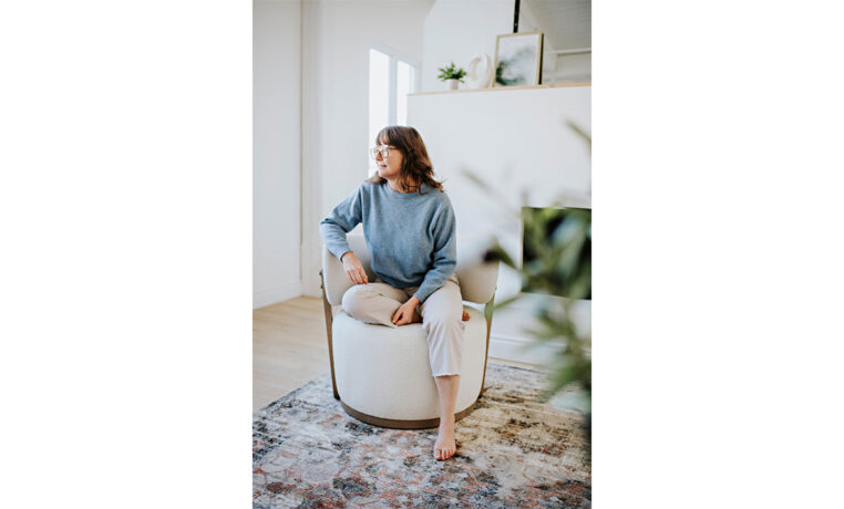 woman relaxing in a custom white swivel chair with exposed wood frame