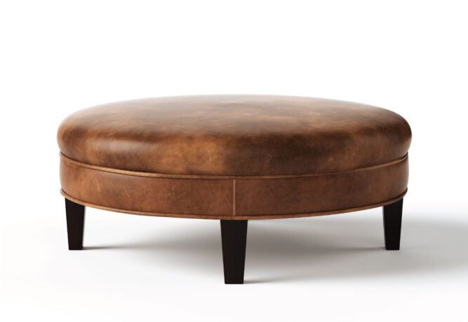 Round Carlisle ottoman from Vogel by Chervin in brown leather and espresso legs with a flat top